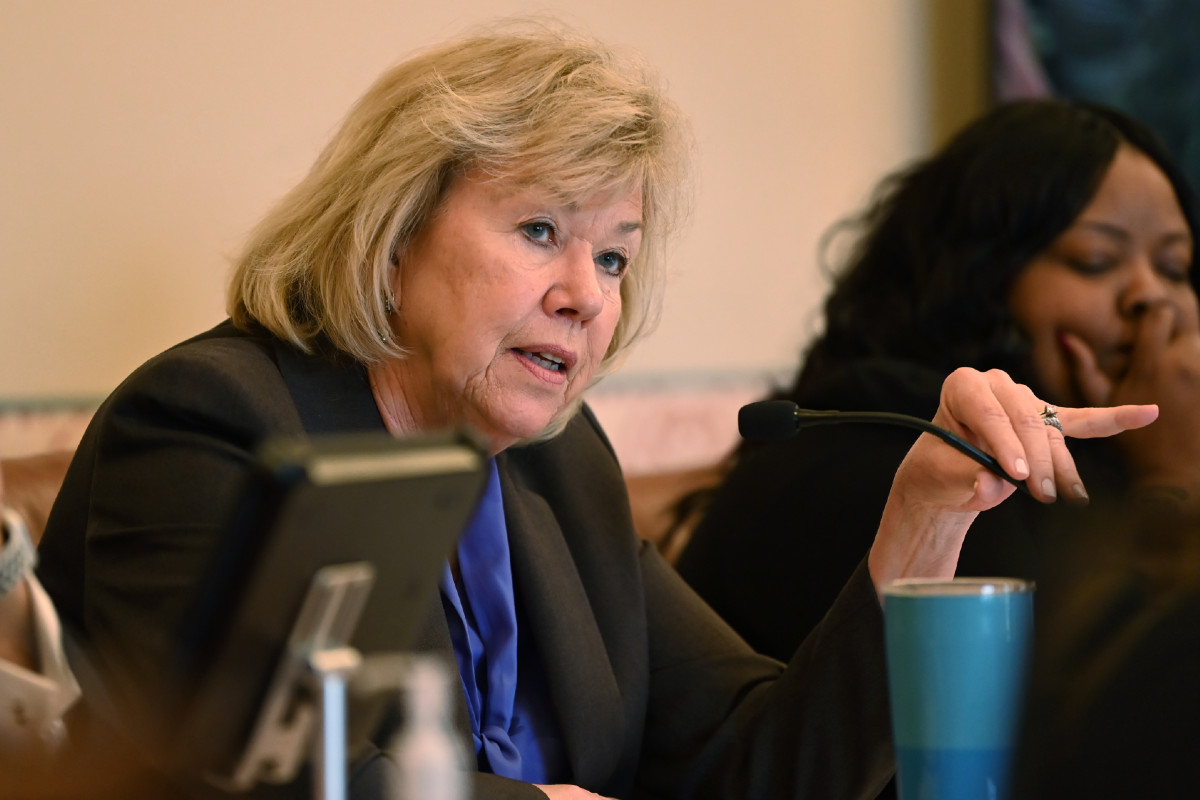 Senator Morrison with a hand on a microphone while speaking during a committee hearing.