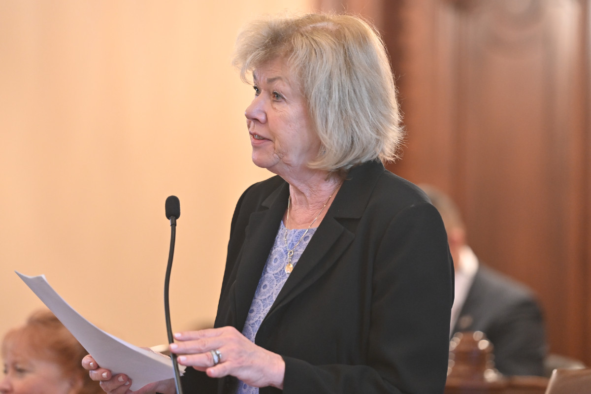 Senator Morrison holding a piece of paper and speaking into a microphone in the Senate chamber.