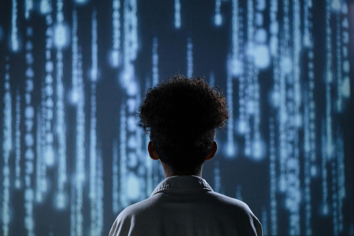 The back of a young adult against a digital-looking background.